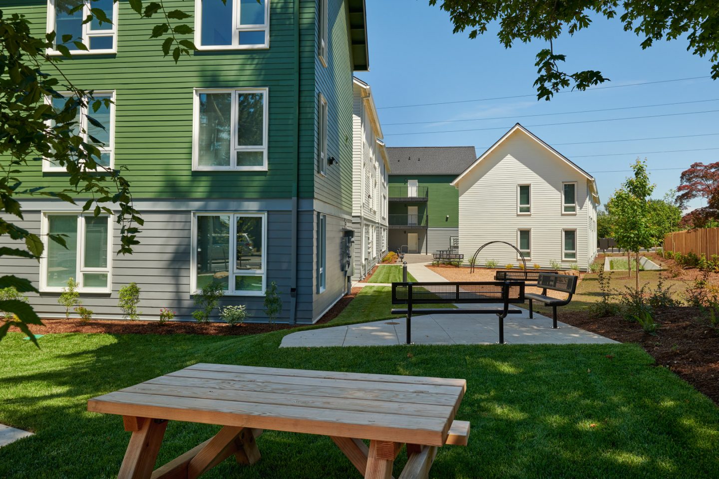 Nestled Between Apartment Buildings, A Shaded Picnic Table Sits on A Bed Of Bright Green Grass In The Courtyard.