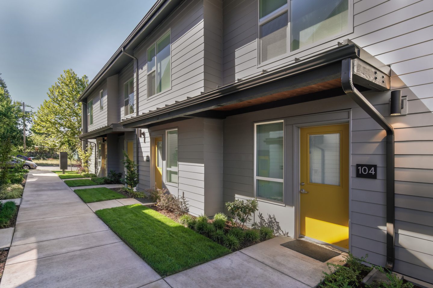 Yellow Doors At The Front And Back Of The Apartments Provide Lead Residents Into Pathways To Community Areas.