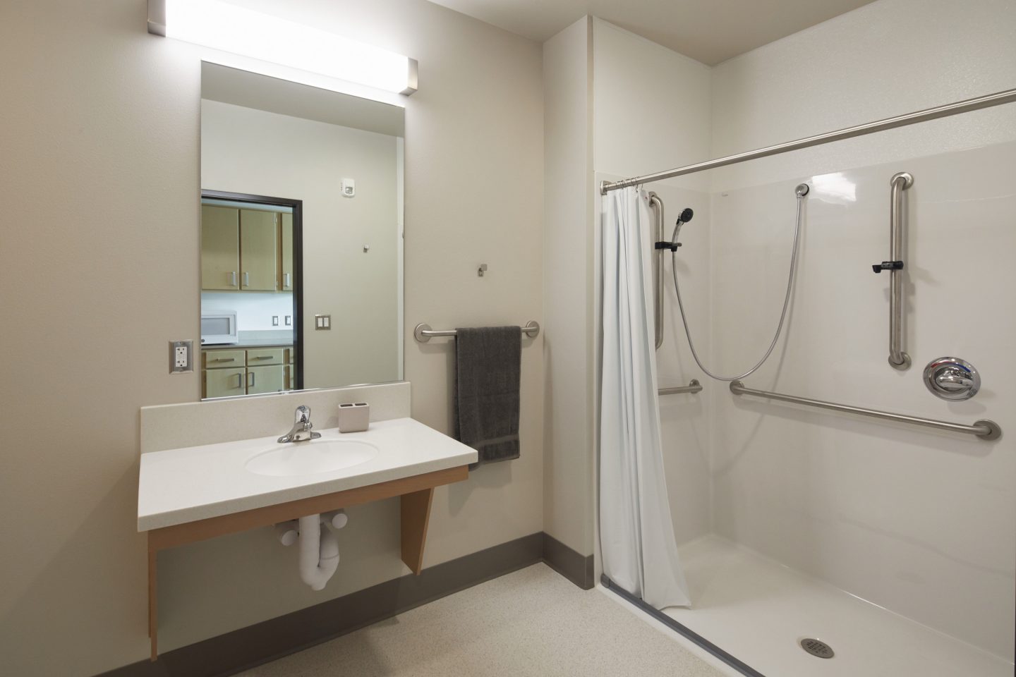 Brightly Lit Bathrooms Have Large Walk-In Showers And Grab Bars.