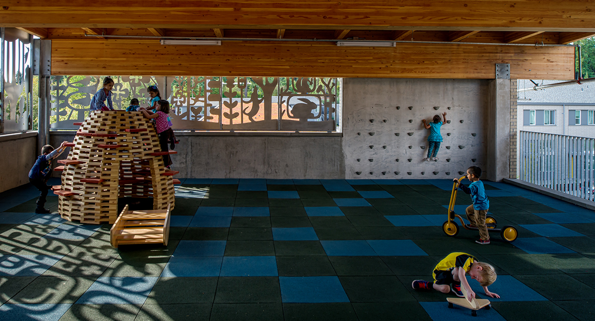 Children Playing In Indoor Playground With Metal Artwork Creating Shadows