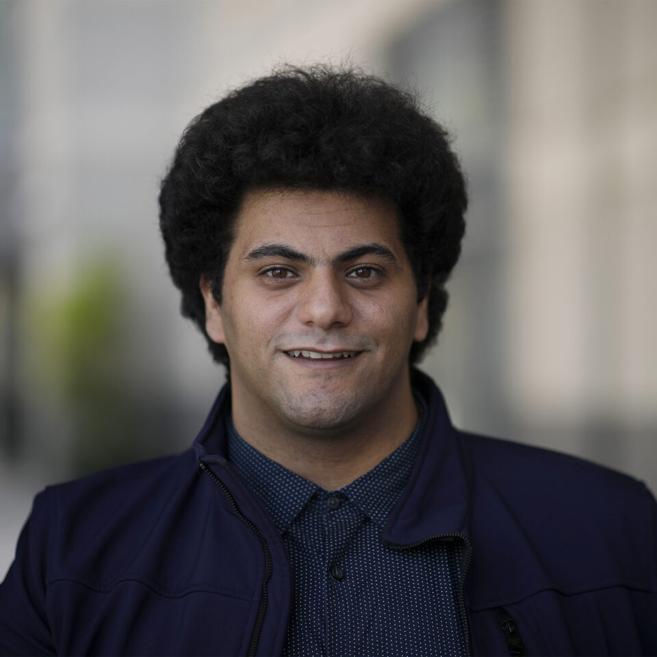 Muhammed El-Sayed smiling in front of a building.